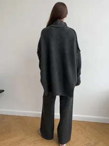 Back view of a charcoal grey oversized turtleneck sweater and matching knit trousers set.