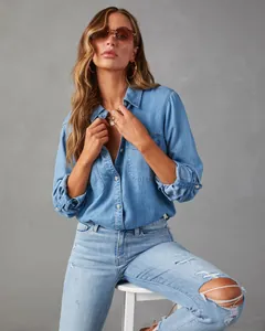 Close-up of a light blue denim long-sleeve shirt on a model with a grey background.