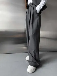 Gros plan sur un pantalon de costume gris à jambes larges, taille haute et au tombé fluide