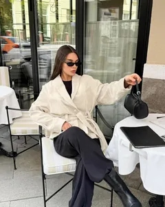 Schicke beige Vintage-Wildlederjacke mit Gürtel, getragen von einem Model in einem gemütlichen Cafe