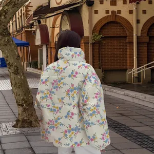 Stylish white puffer jacket with colorful floral print in a trendy outdoor street setting