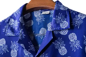 Detail view of blue Hawaiian shirt featuring white pineapple print and collar label