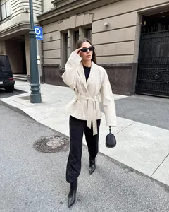 Weibliches Model in beiger Wildlederjacke und schwarzer Hose auf einer Stadtstraße