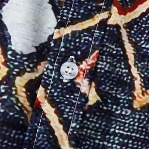 Close-up detail of white button and stitching on men's floral beach holiday shirt