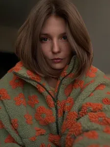 Gedetailleerde close-up van een groene fleece trui met oranje bloemenpatronen erop
