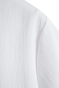 Macro close-up view of white textured seersucker fabric on summer short-sleeve shirt for men