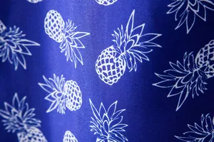 Close-up detail of premium blue Hawaiian shirt fabric with stylish white pineapple pattern