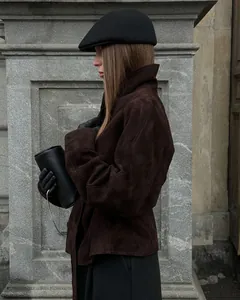 Seitenansicht einer Frau in brauner Wildlederjacke mit Stehkragen und schwarzer Kappe