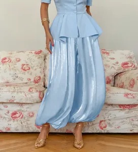 Dettaglio dei pantaloni a lanterna azzurro metallizzato con vestibilità ampia e lucida.