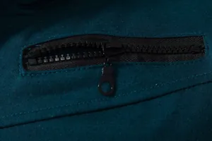 Gros plan du zip noir fonctionnel sur un gilet de sport respirant bleu canard foncé