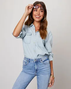 Detail view of a woman wearing a light blue denim shirt with double breast pockets
