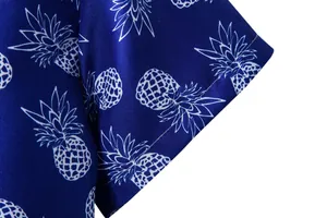 Close-up of the intricate white pineapple print on a blue men's Hawaiian short sleeve shirt