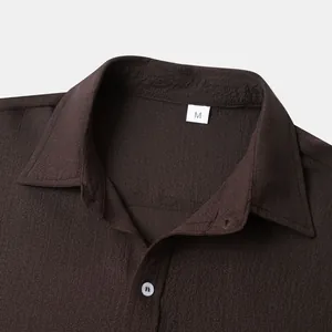 Close-up detail of dark brown textured men's shirt collar with white button and size M tag