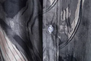 Detailed macro view of the button and stitching on a grey abstract print men's shirt