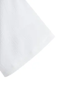 Close-up of white textured fabric on a men's short-sleeved summer shirt sleeve.