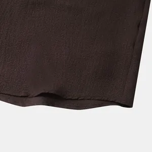 Detailed macro view of the dark brown textured fabric and hem stitching on a men's shirt