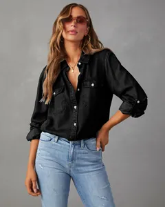 Professional detail shot of a women's black long-sleeved denim shirt with pocket details.