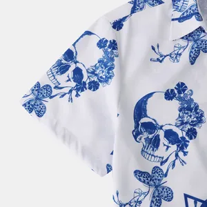 Detailed macro view of blue skull and floral butterfly prints on white men's beach shirt