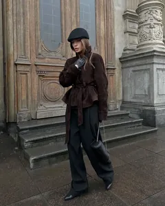 Stilvolle braune Retro-Wildlederjacke für Damen mit Gürtel in Vintage-Architektur-Kulisse