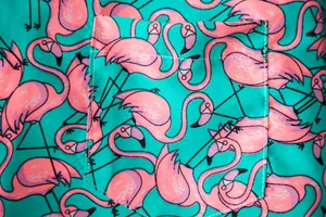 Macro view of vibrant pink flamingo pattern on a teal men's short sleeve shirt pocket
