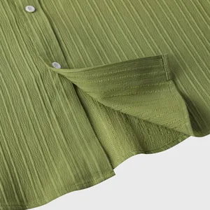 Detalle de cerca de la tela verde con textura y botones blancos de camisa de hombre.