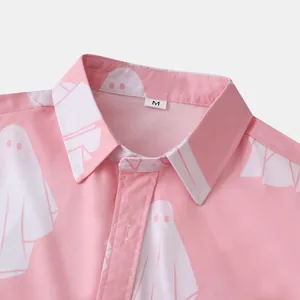 Dettaglio ravvicinato di una camicia rosa a maniche corte con motivi a fantasmi bianchi.