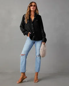Full body lifestyle shot of a model wearing a black denim shirt and ripped blue jeans.
