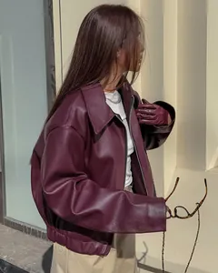 Detail van een stijlvol bordeauxrood oversized kunstleren motorjack gedragen door een model.