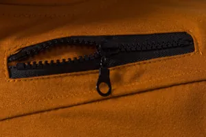 Détail en gros plan d'une fermeture éclair noire sur un gilet décontracté jaune moutarde.