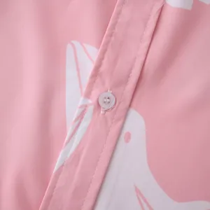 Dettaglio ravvicinato di una camicia rosa a maniche corte con motivi di uccelli bianchi.