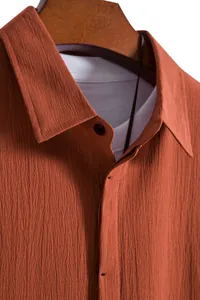 Close-up of textured fabric and collar of a men's rust orange short sleeve shirt