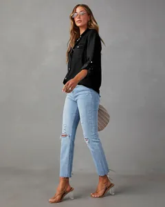 Full view of black denim shirt paired with light blue ripped jeans on a model