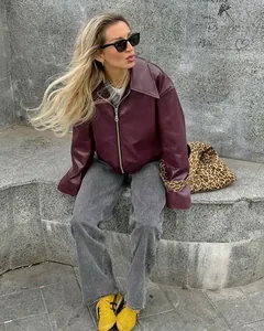 Oversized bordeauxrood imitatielederen motorjack gecombineerd met grijze jeans