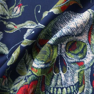 Κοντινό πλάνο υφής υφάσματος που δείχνει λεπτομερές τύπωμα νεκροκεφαλής και λουλουδιών.
