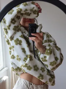 Gedetailleerde opname van een wit fleece sweatshirt met groene bloempatronen erop