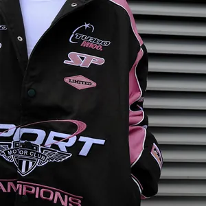 Close-up detail of a pink and black varsity racing jacket featuring intricate embroideries