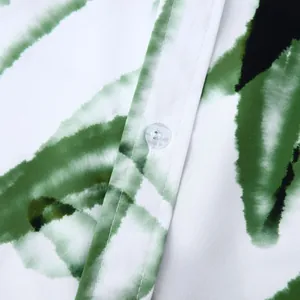 Détail macro de l'imprimé tropical vert et du bouton sur chemise hawaïenne homme