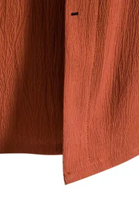 Close-up detail of rust orange crinkle fabric texture on men's short sleeve casual shirt