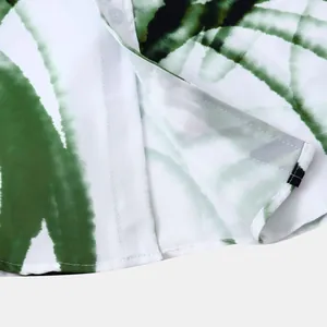 Détail rapproché montrant les coutures de qualité et l'imprimé floral hawaïen vert de la chemise