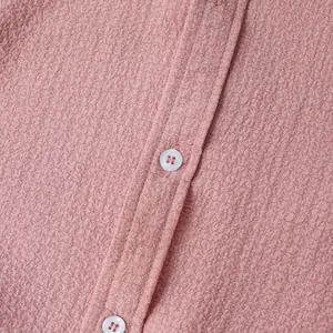 Close-up of pink textured men's short sleeve shirt showing white buttons and fabric detail