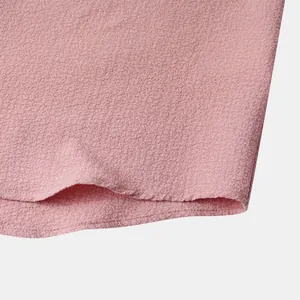 Macro detail showing the pink textured fabric and neat stitched hem of a men's casual shirt