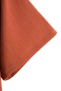 Detailed texture view of men's rust orange short-sleeved shirt fabric and hem stitching