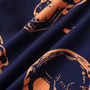 Detailed close-up of orange skull pattern on navy blue woven fabric for Halloween shirt