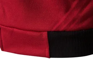 Vue macro détaillée montrant les coutures fines et l'ourlet noir côtelé d'un gilet de sport rouge