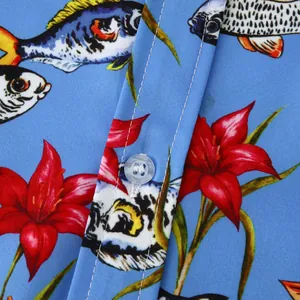 Macro detail of tropical fish and red floral print on men's light blue beach holiday shirt
