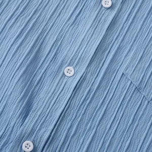 Primer plano detallado de la tela azul claro arrugada y botones blancos de camisa
