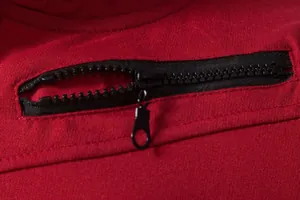 Gros plan détaillé d'une fermeture éclair noire sur un gilet de sport rouge pour hommes.