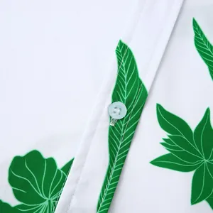 Détail en gros plan d'une chemise hawaïenne blanche avec des imprimés de feuilles vertes.
