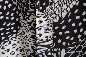 Close-up of men's casual shirt featuring black and white snake print and clear button.