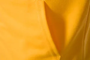 Zoom sur le tissu jaune respirant et les coutures doubles d'un gilet de sport pour homme.